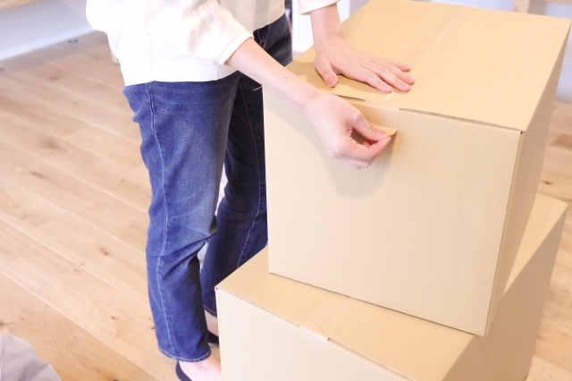 ガチャガチャの景品を段ボールに梱包している女性