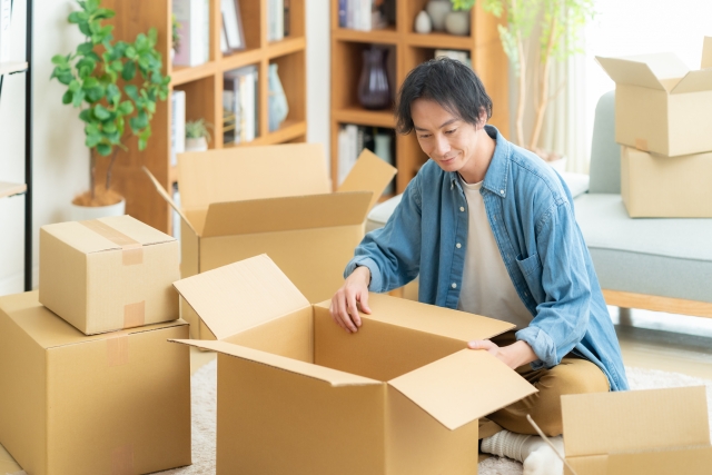 男性が引っ越し先へ持って行くカプセルトイを仕分けている